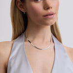 Woman wearing a silver necklace against a plain background